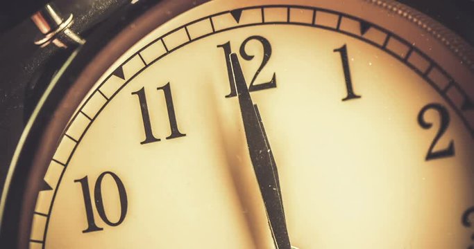old grunge vintage alarm clock is showing midday or midnight movement. It is twelve o'clock, holiday happy new year festive and christmas or lunch concept, time-lapse effect