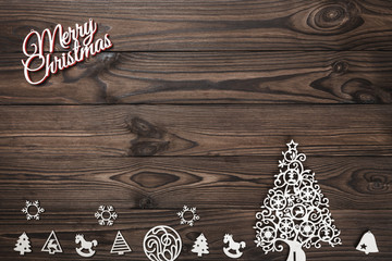 View from above of a Merry Christmas inscription and handmade tree toys on wooden background,...