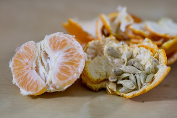 Tasty ripe peeled mandarin on a wooden table. Tangerine in pieces and skin. Wooden table.