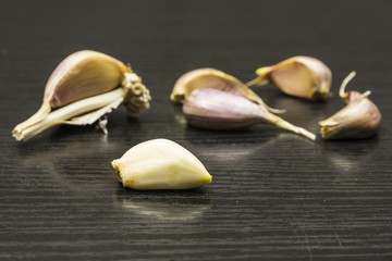 Peeled clove on the background of the torn bulb of garlic.