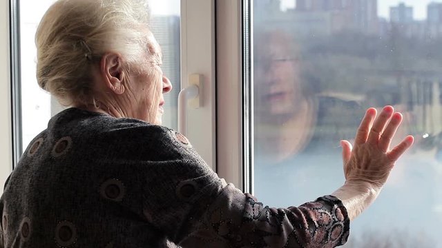 Lonely old woman looking out the window. Loneliness in old age