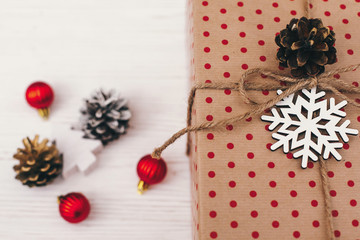 merry christmas and happy new year concept. stylish wrapped gift box with ornaments and golden pine cone. space for text. seasonal greetings, happy holidays. xmas present