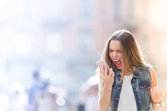 Angry and upset teenager screaming at the mobile telephone