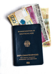 German diplomatic passport with bills from different countries of the world, isolated