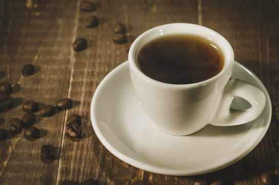 white cup with coffee on a dark wooden background/white cup with coffee on a dark wooden background. Selective focus