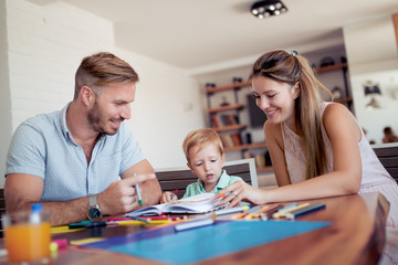 Fototapeta premium Mother and father drawing together with their child.