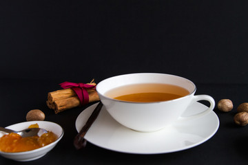 White porceilance china tea cup over black background with marmelade and spices around it