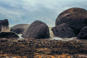 Steine am Strand mit Wellen und Gischt