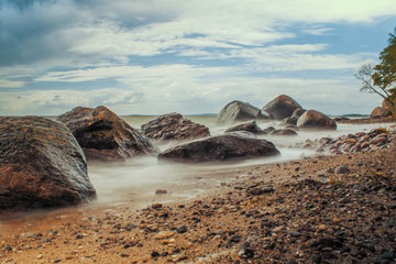Steine am Strand mit Wellen, weichgezeichnet