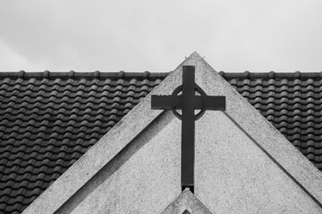 Abstract black and white image of metal holy cross or crucifix on the top of white church. (Selective focus)