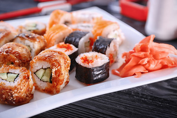 Plate with tasty sushi rolls on table, closeup