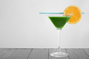 Glass of wheat grass juice on light background
