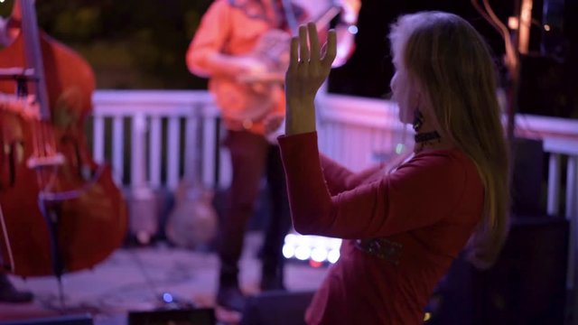 Pretty woman dances to the live music at an outdoor concert at a restaurant.