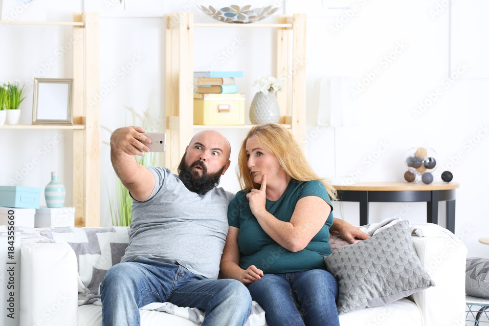 Poster overweight couple taking selfie at home