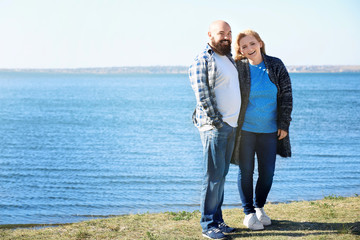 Overweight couple near river on sunny day