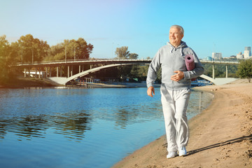 Mature man with mat walking near river