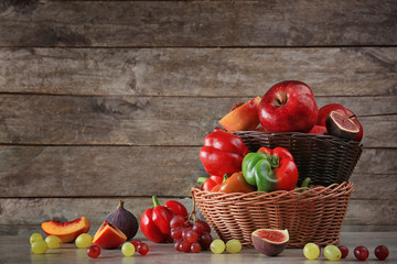 Fototapeta na wymiar Basket with different fruits and vegetables against wooden background