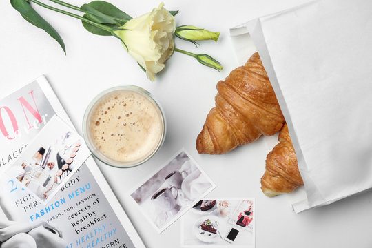 Composition with croissants in paper bag and coffee on white background