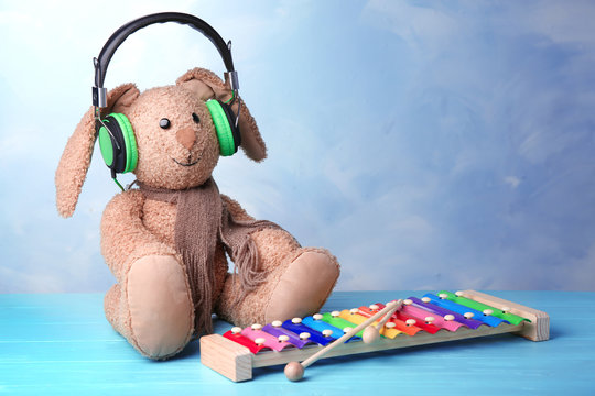 Toy with headphones on table against color wall. Baby songs concept