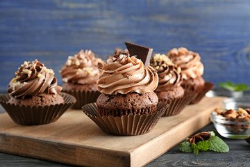 Tasty chocolate cupcakes on wooden board