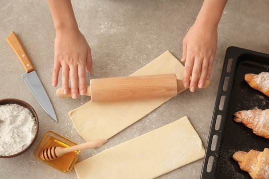 Woman rolling out puff pastry on table