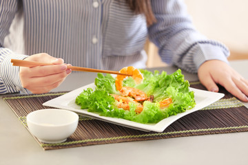 Young woman eating shrimps at table