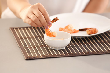 Young woman eating shrimps at table