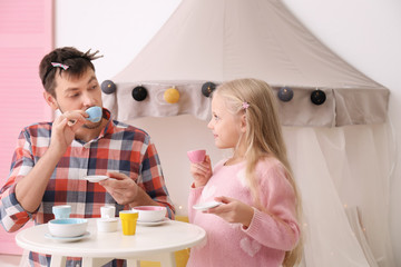 Cute little girl playing with father at home