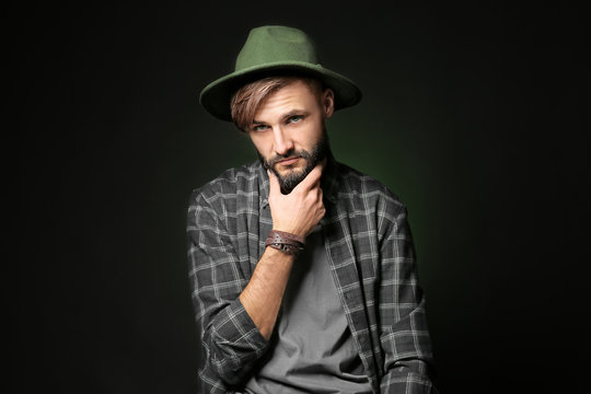 Thoughtful young hipster man on dark background