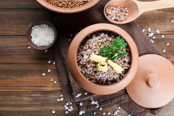 Pot with cooked buckwheat on table