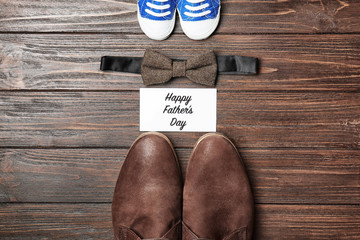 Bow tie, big and small shoes on wooden background. Father's day composition