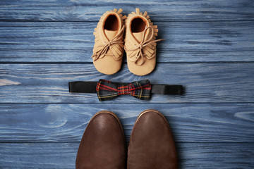 Bow tie, big and small shoes on wooden background. Father's day composition