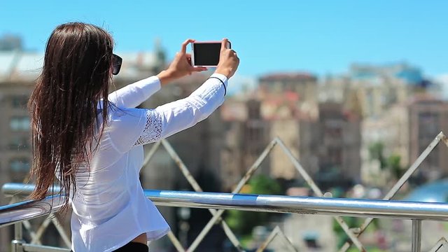 Businesswoman makes photos or records videos on smartphone. Beautiful girl with red cell phone