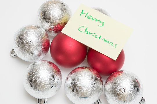 Merry christmas writen on yellow sheet and christmas ball on white background