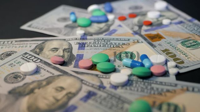 Pills falling on dollar banknotes, expensive medication, pharmaceutical business. Pharmacy theme. Multicolored Pills and Capsules on money. Slow motion.