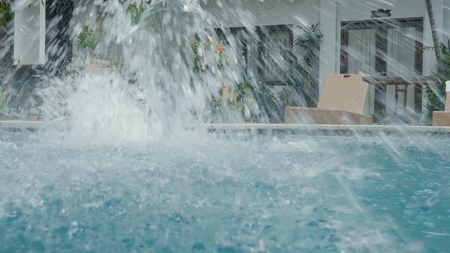 Young man on summer vacation jumping flip into blue pool water for refreshment on hot sunny day. Guy diving into empty pool in luxury resort