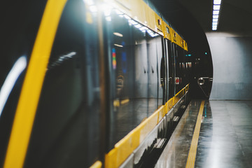 Dark interior of subway station with modern train with closing doors; perspective view of empty...