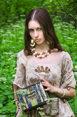 young woman in vintage dress holding an old chest