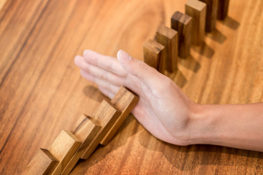 businessman hand stop dominoes continuous toppled or risk with copyspace.