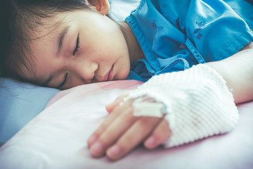 Illness asian child admitted in hospital with saline intravenous on hand.