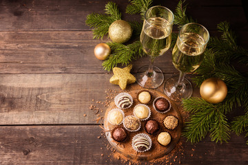 Chocolate sweets and two glasses of champagne on a New Year wooden background. Christmas concept. Copy space. View from above