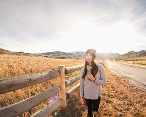 beautiful girl in warm clothes in spring or autumn sits in the sunlight in a mountainous area