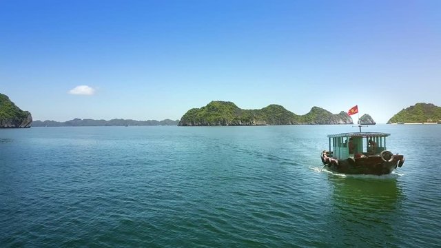 Flycam Shows Tourist Boat Speeding on Azure Bay against Islands
