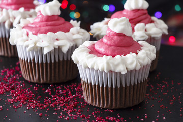 Three Christmas homemade chocolate cupcake with pink cream cheese frosting. Blur light and dark background. Selective focus.