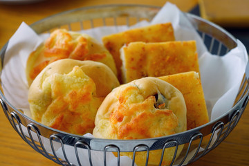Slices of fresh focaccia and cheese rolls in a bread basket