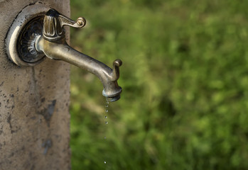 A drop of water close up. Old copper tap.