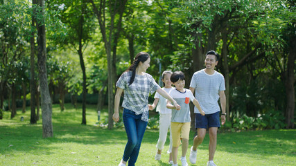 Chinese family smiling & walking together in park