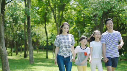 Chinese family smiling & walking together in park