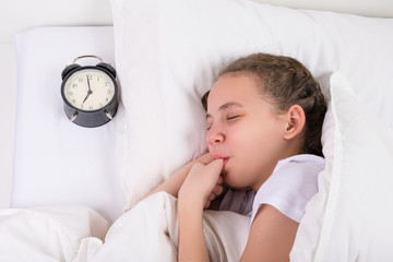 girl sleeps and sucks her thumb, a habit since childhood