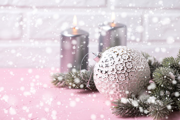 Big white ball, silver candles and  branches fur tree on pink  background against  white wall.